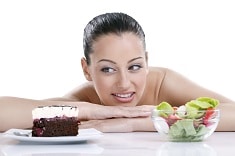 Dieting concept,  beautiful young woman choosing between healthy food and tasty cakes