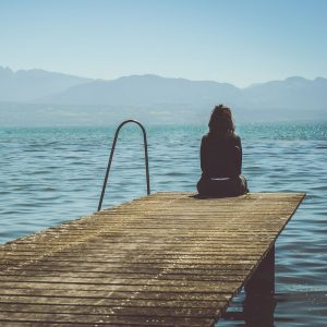 woman sitting on jetty feeling lonely